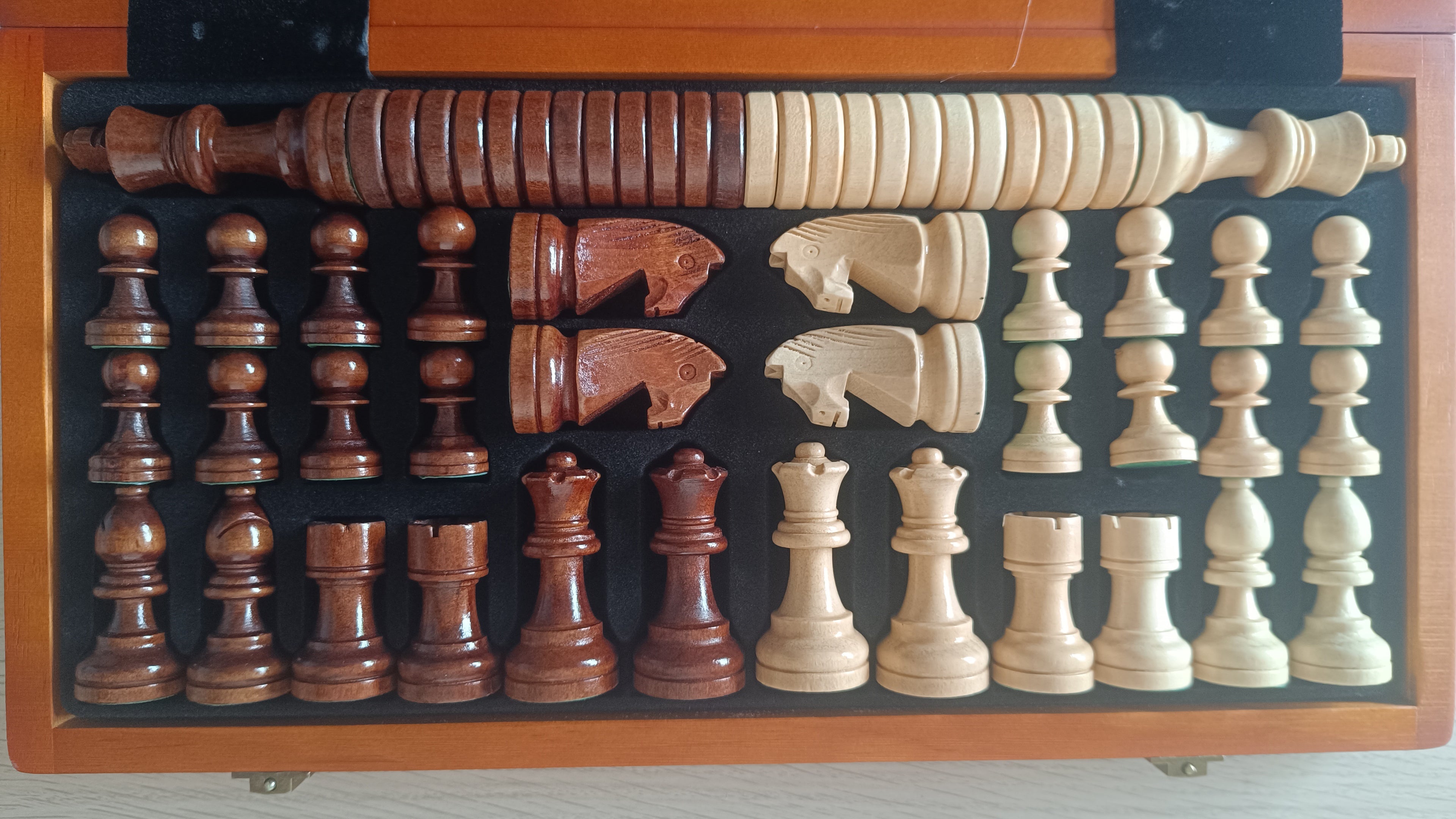Pièces d'échecs rangées dans leurs compartiments de rangement en bois du coffret