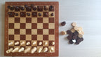 Vue de dessus de l'échiquier avec les pièces d'échecs alignées et les pions de dames posés à côté