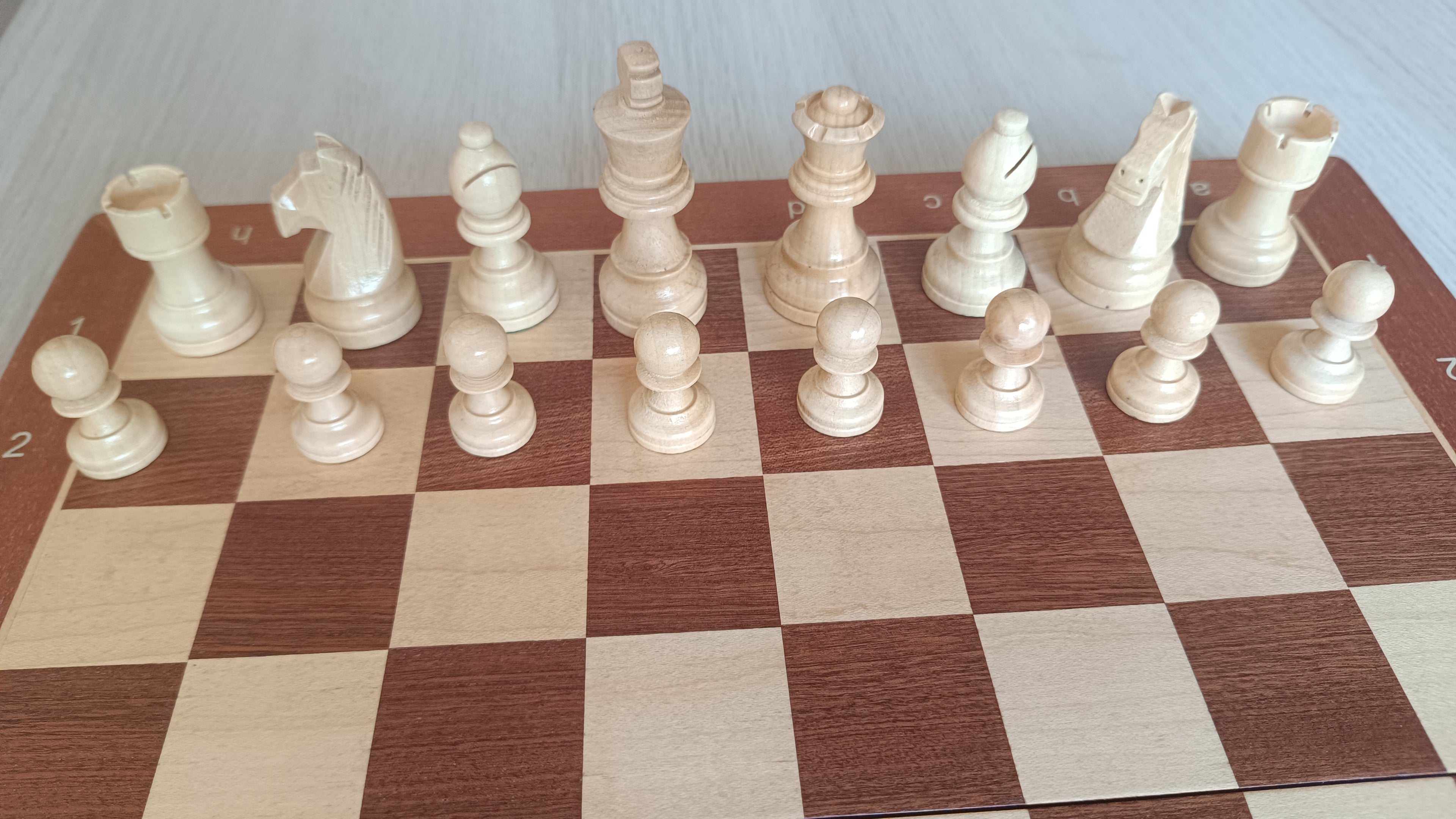 Rangée complète des pièces d'échecs claires aimantées sur l'échiquier en bois