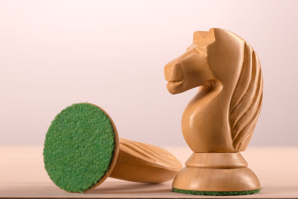 Gros plan sur un cavalier clair en acacia du jeu d'échecs Queen's Gambit 1957 avec sa base feutrine